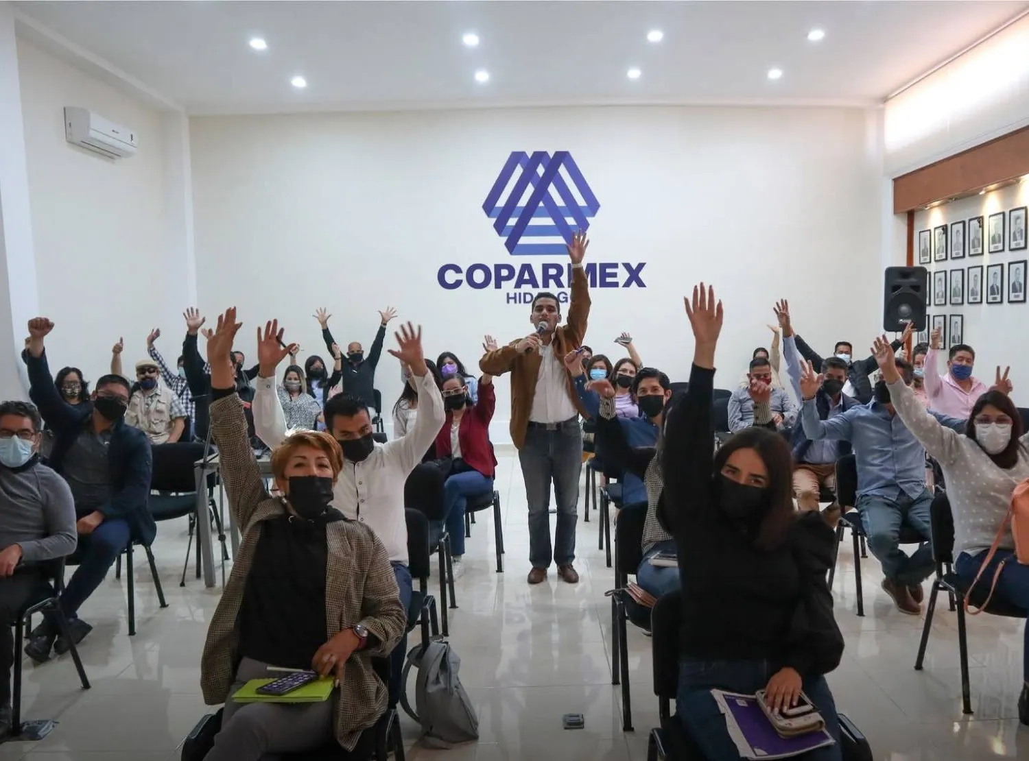 Taller de marketing inmobiliario con asistentes levantando la mano